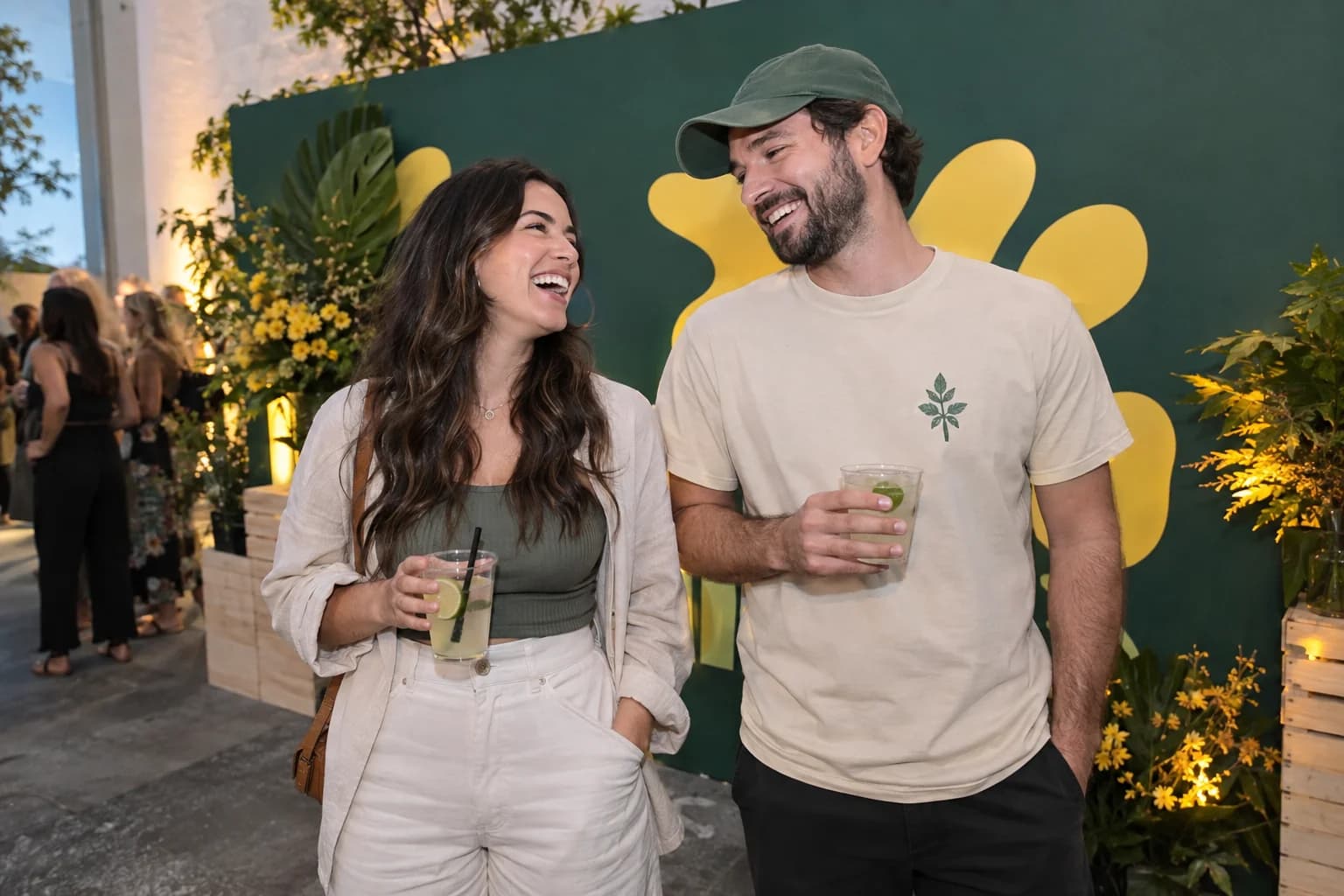 Two friends laughing together in front of a green and yellow event backdrop