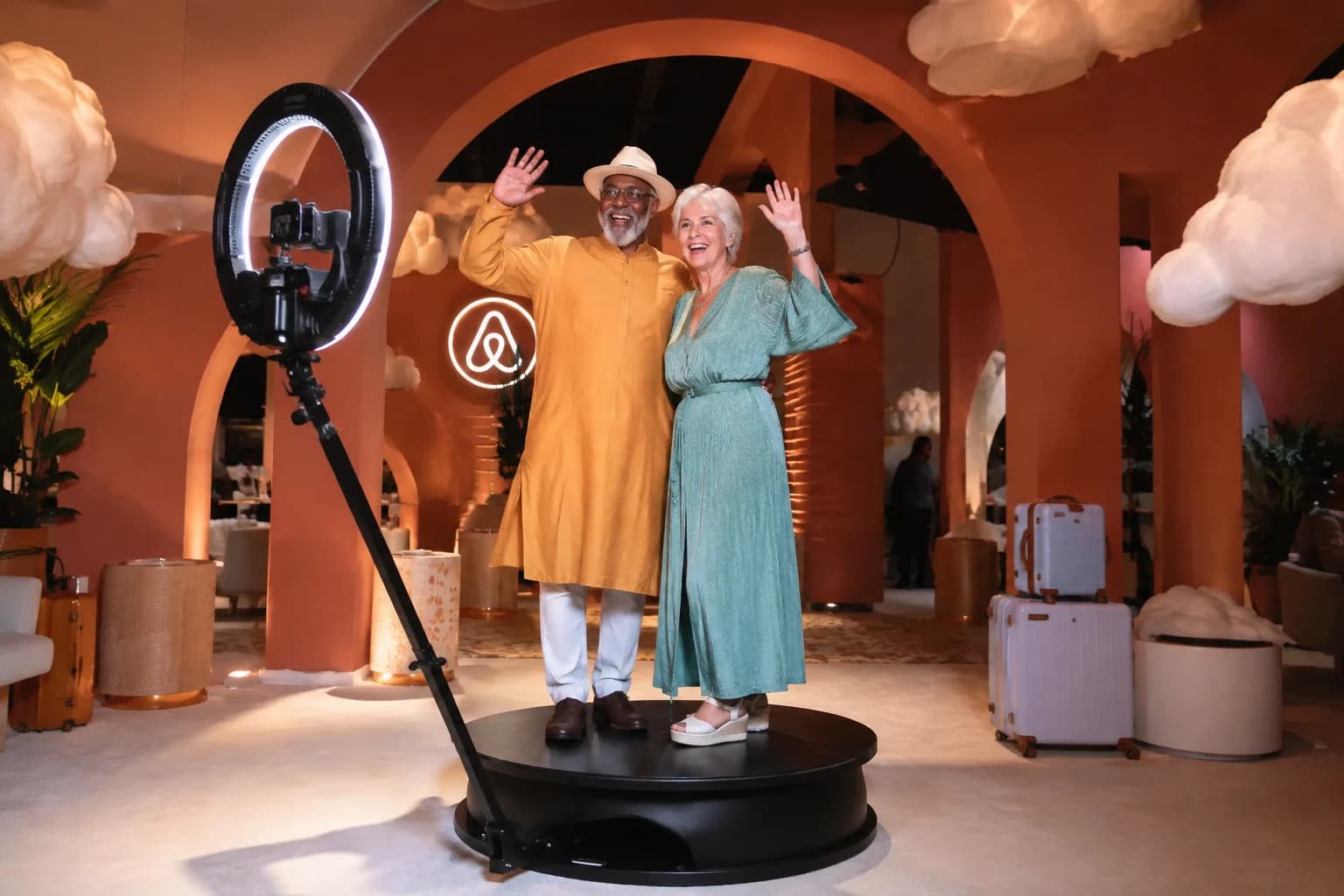Friends posing on a circular 360 platform at a colorful travel-themed activation